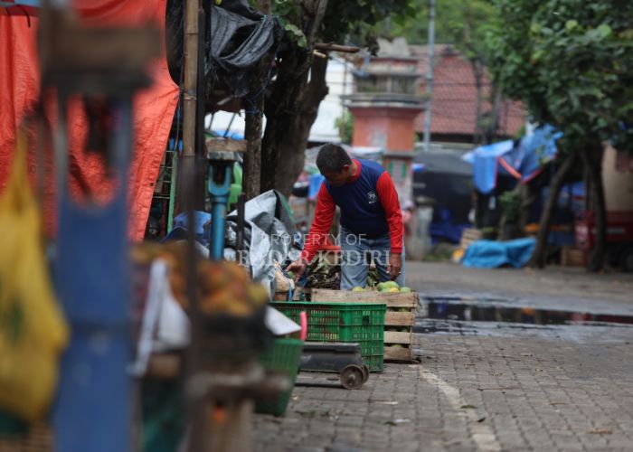 TERDAMPAK TOL: Seorang pedagang buah menggeser keranjang yang ada di tepi jalan.