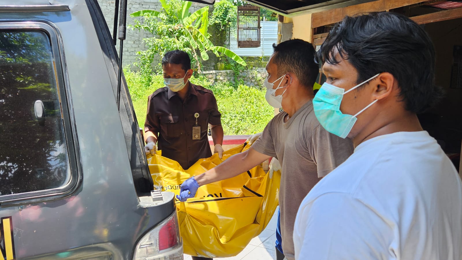 MEMBUSUK: Petugas polisi memasukan jasad ke mobil jenazah.