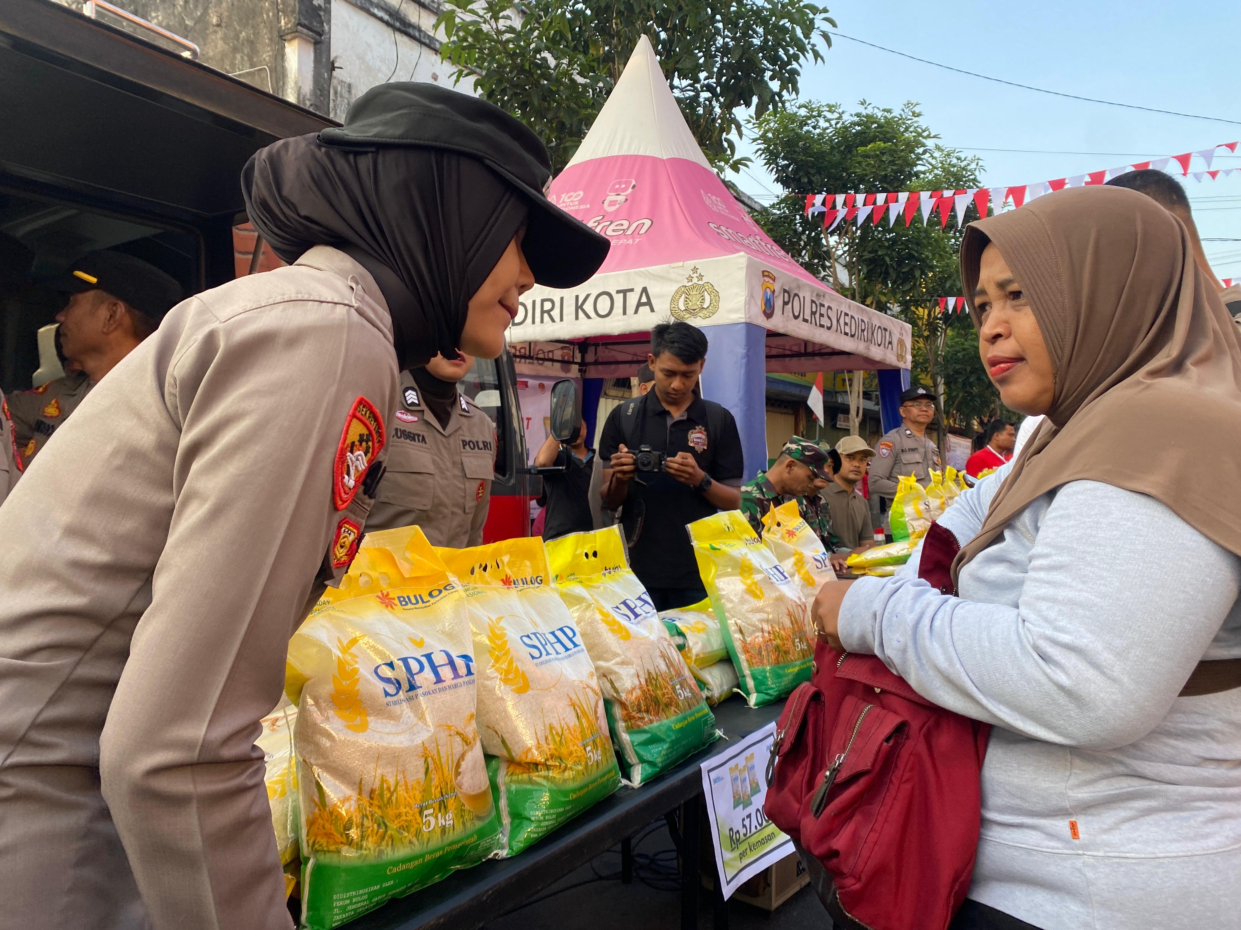 TEKAN HARGA: Anggota polwan Polres Kediri Kota ikut menyalurkan beras SPHP dari Bulog Cabang Kediri