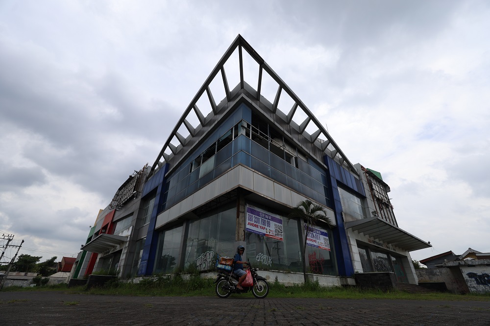 Seorang pengendara motor melintas di depan gedung Dhoho Square Kediri yang mangkrak sejak 2015. Kabar baiknya, gedung tersebut dilirik investor Jakarta