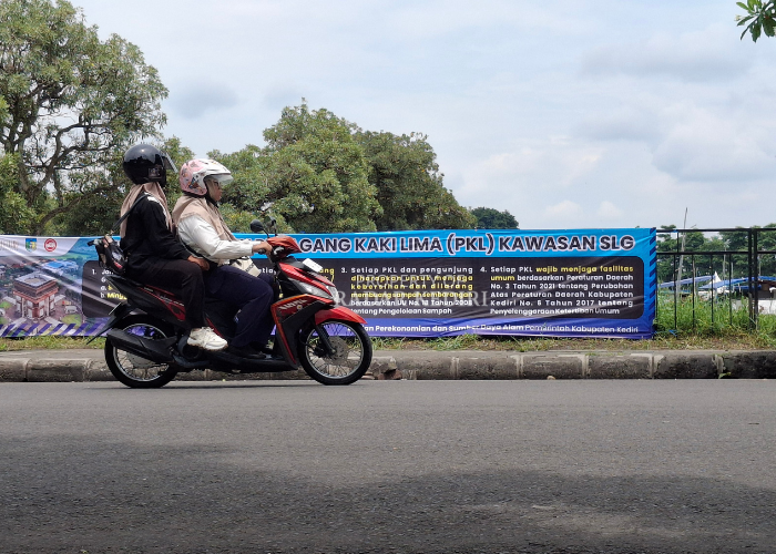 ATURAN BARU: Pengendara melintas di depan banner kebijakan anyar Pemkab Kediri di Kawasan SLG. (Foto : ASAD MS)