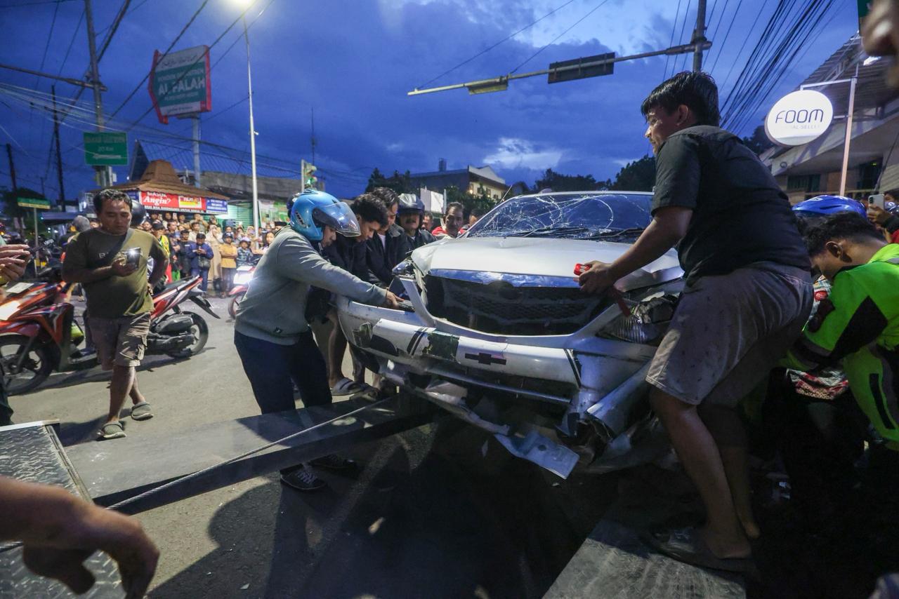 DRAMATIS: Warga bersama polisi menarik mobil Xenia yang menjadi korban Bus Harapan Jaya.