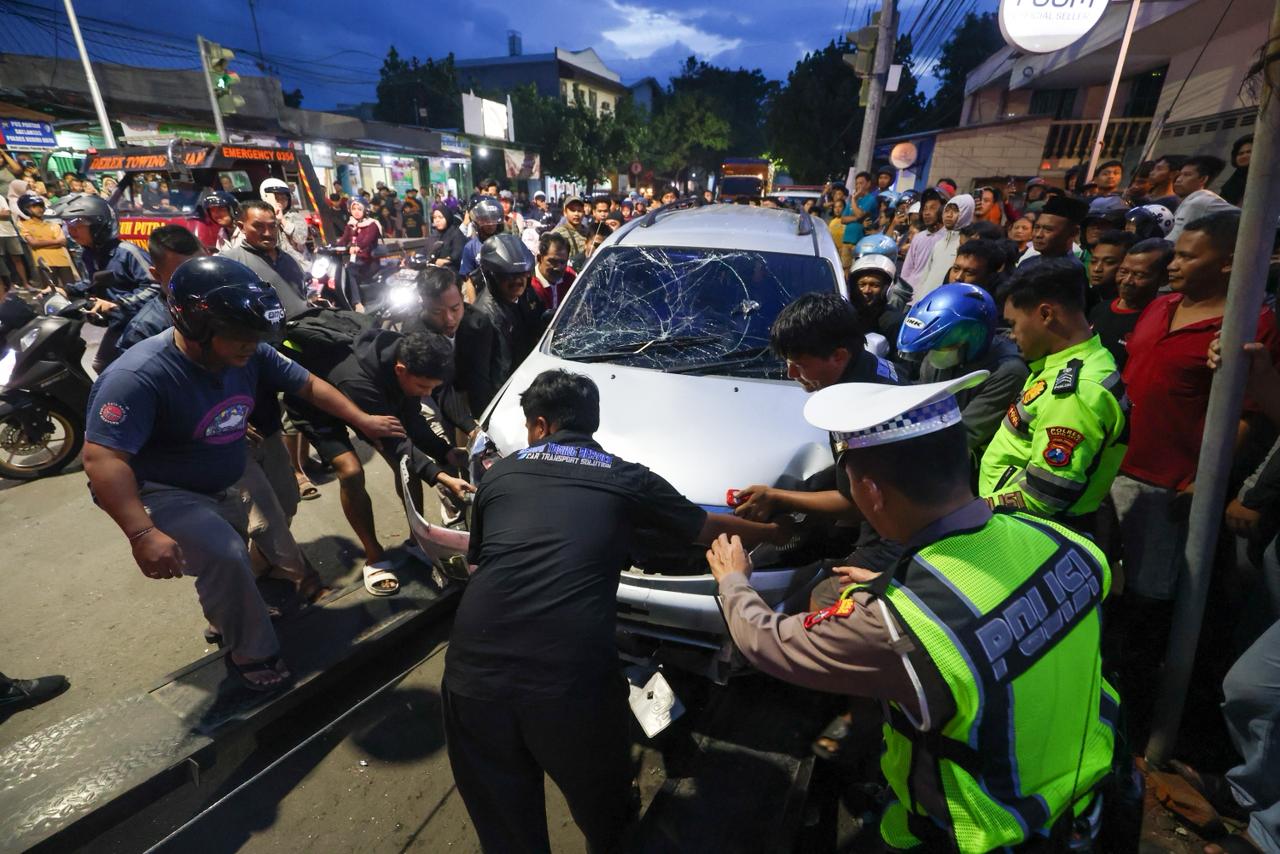 GEMPAR: Polisi bersama warga di Perempatan Muning Kota Kediri mendorong mobil Xenia ditabrak Bus Harapan Jaya.