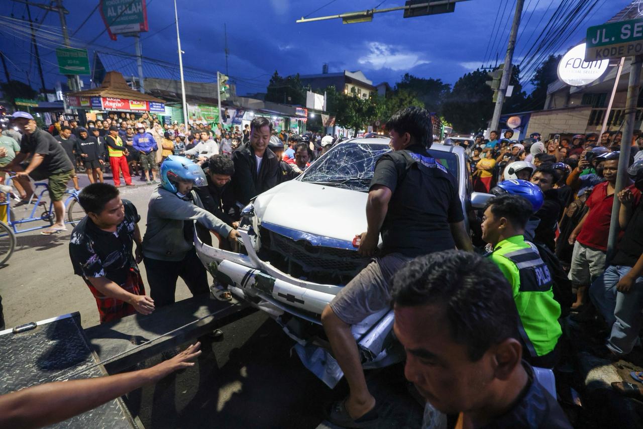 RINGSEK: Warga beramai-ramai memindahkan mobil Xenia yang menjadi korban laka Bus Harapan Jaya di Perempatan Muning, Kota Kediri.