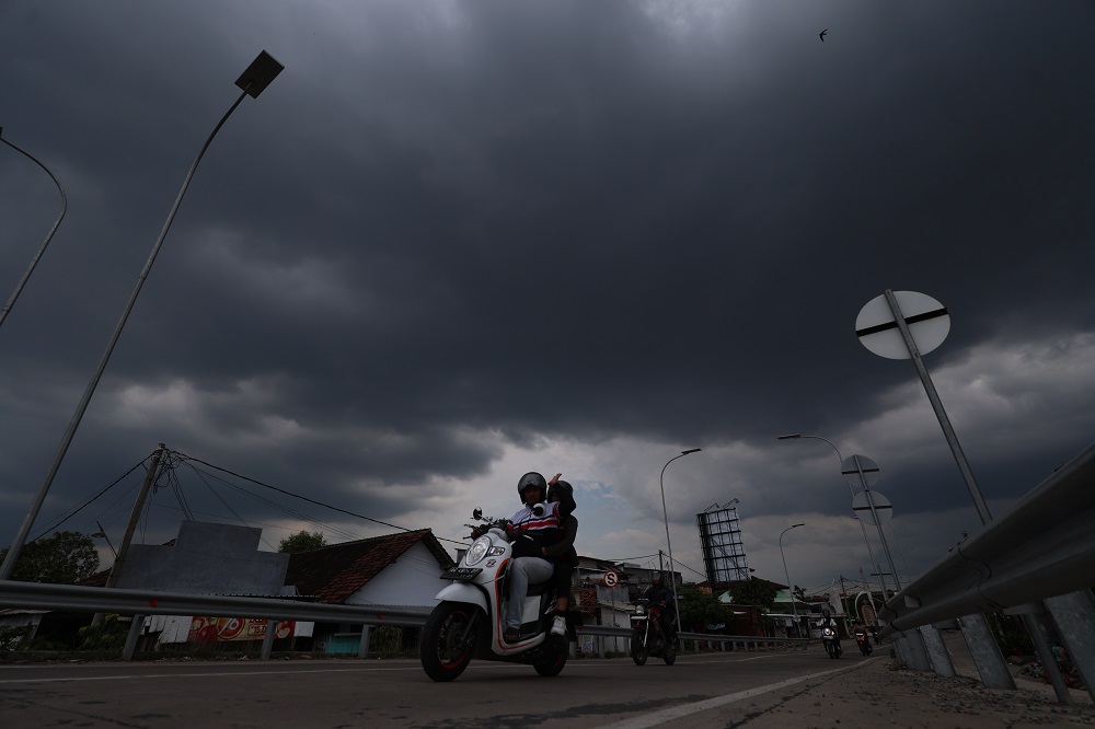 MENDUNG GELAP: Seorang pengendara motor melewati Jembatan Jongbiru. Cuaca ekstrem, warga diminta selalu waspada.