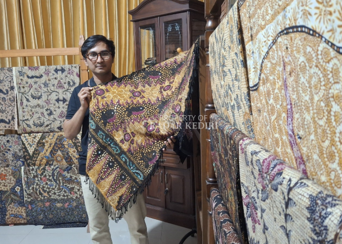 Rifky tunjukkan karyanya dengan sang istri. Yakni batik tulis di kain serat nanas dengan motif lereng gening sritanjung. (Foto: Asad MS)