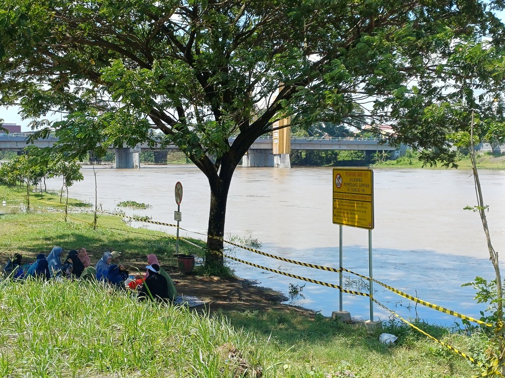 Pengunjung Taman Brantas nampak bersantai di bantaran sungai. Debit air Sungai Brantas mengalami kenaikan pada Sabtu (31/1).