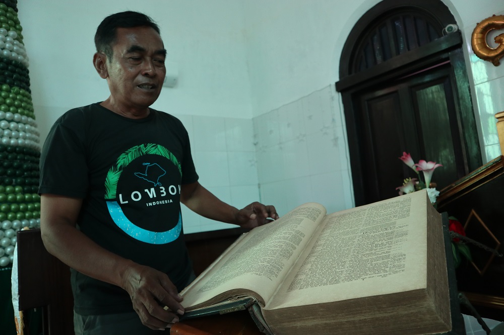 BERSEJARAH: Lorens Hendrik menunjukkan Alkitab kuno berusia 158 tahun di Gereja Merah Kota Kediri. Tahun ini, Alkitab itu diusulkan untuk direstorasi oleh Disarpus Kota Kediri.