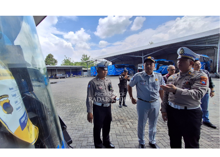 Polda Jatim sedang memasang tanda bahwa bus layak jalan. (Foto: Asad MS)