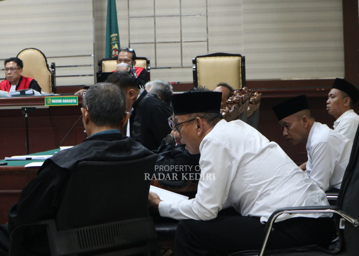 KONSULTASI: Kades Kalirong Imam Jamiin (kiri) berbincang dengan penasihat hukum, dalam sidang kasus rekayasa rekrutmen perangkat desa di PN Tipikor Surabaya.