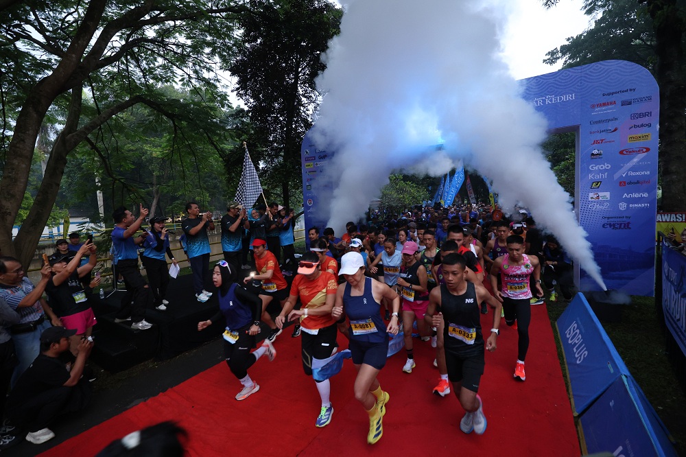 GO!: Wakil Bupati Kediri Dewi Mariya Ulfa mengibarkan bendera yang menandai start bagi para runners kelompok 10K dalam ajang Waru Turi Fun Run 2026 di Bendung Gerak Waru Turi pada 15 Februari.
