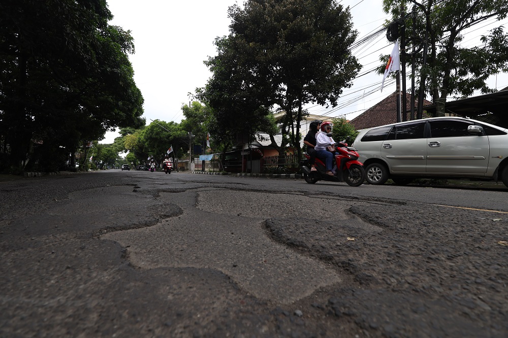 BERBAHAYA: Warga melintas di Jl Imam Bonjol Kota Kediri yang dipenuhi dengan lubang. Dinas PUPR Kota Kediri berencana memperbaikinya pekan depan.