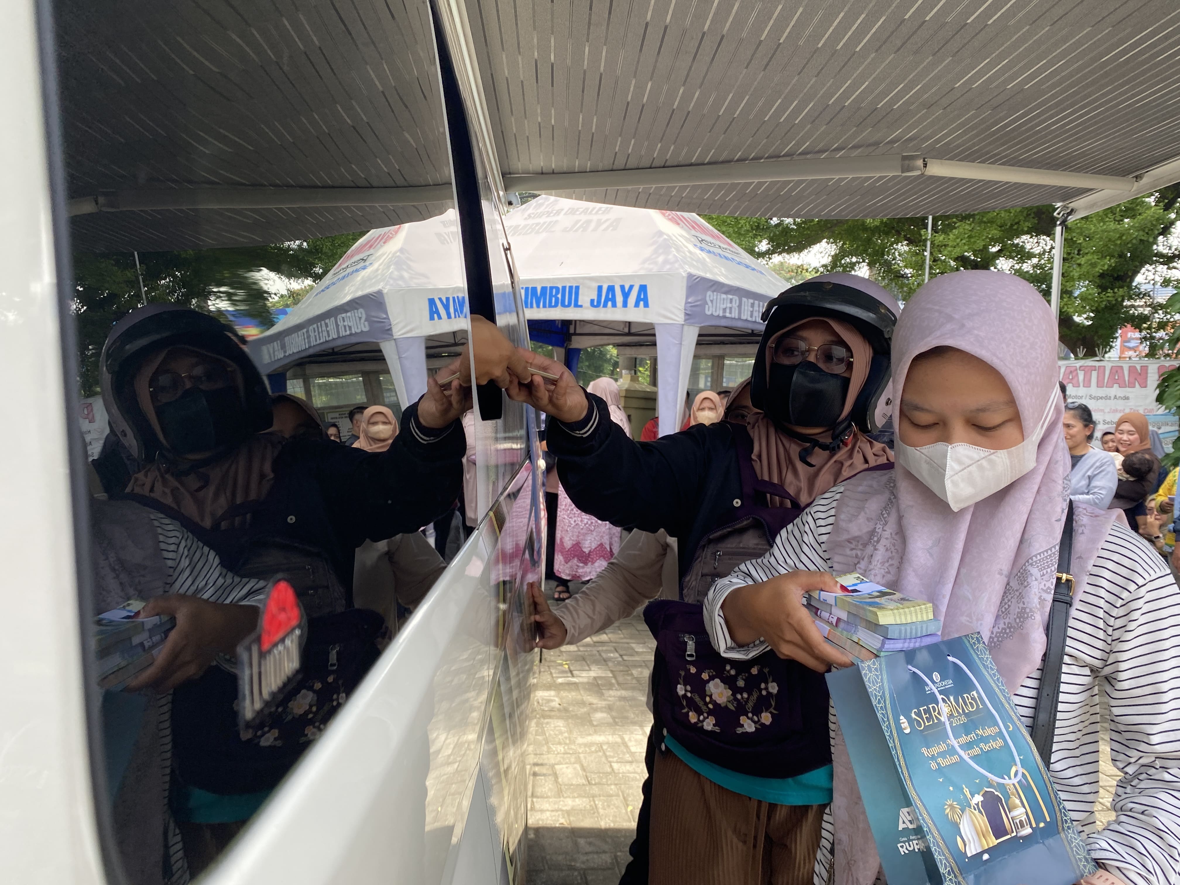 Warga sedang mengantre menukarkan uang baru di mobil Bank Indonesia yang parkir di halaman Masjid Agung, Kota Kediri.