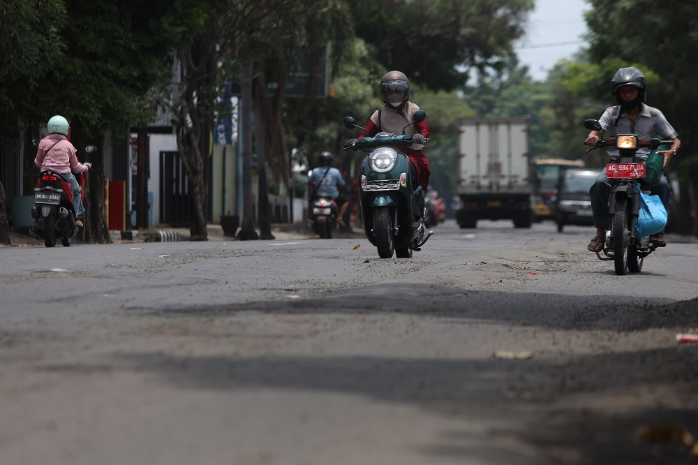 PERLU PERBAIKAN: Pengendara melintas di jalan depan SPBU Kelurahan Singonegaran yang banyak mengalami kerusakan.