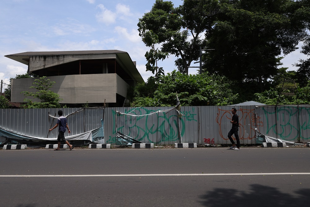 TERKATUNG-KATUNG: Pejalan kaki melintas di dekat seng penutup proyek Alun-Alun Kota Kediri yang mangkrak hingga saat ini.