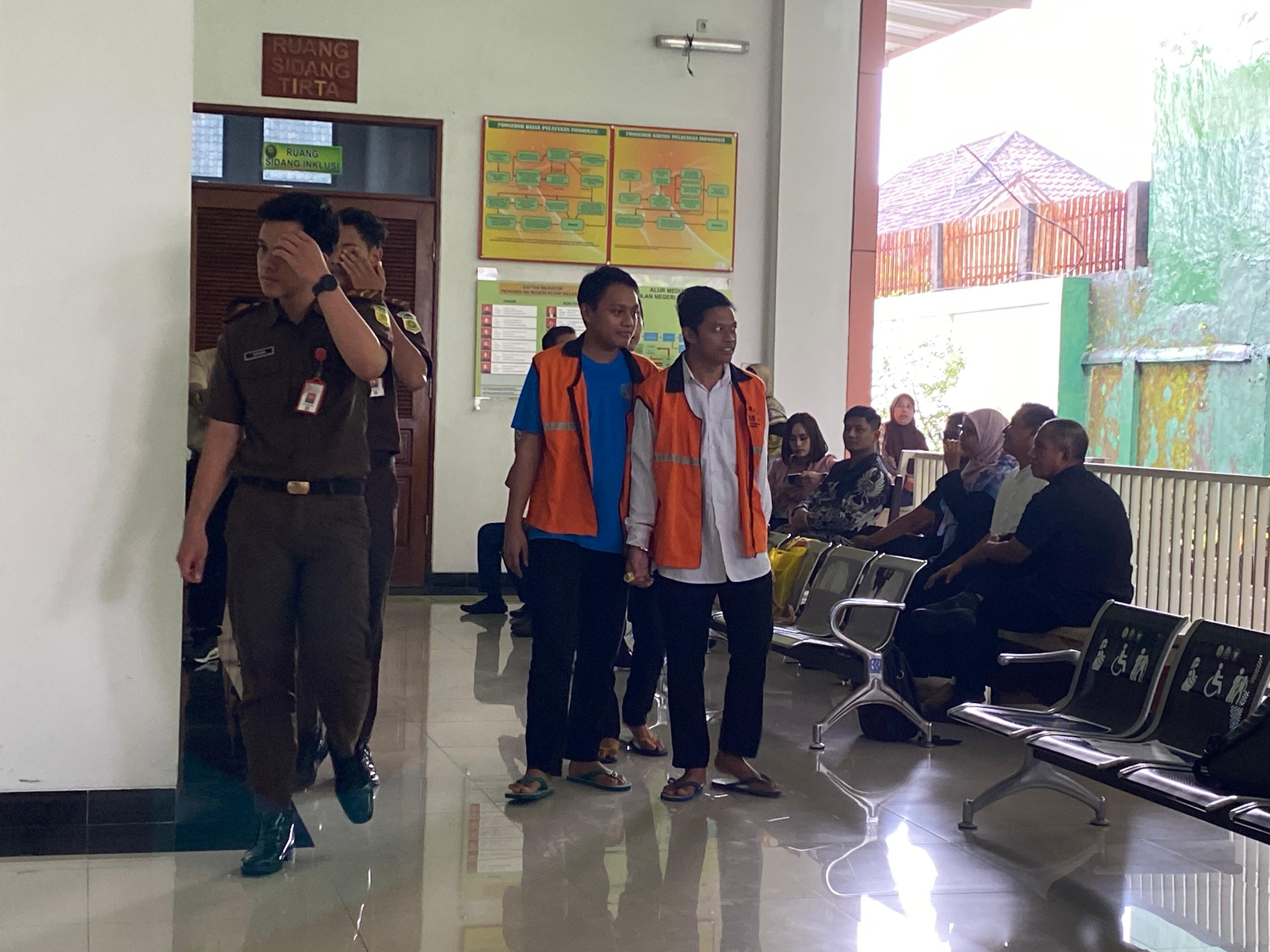 Dua terdakwa pelempar bom molotov berjalan menuju ruang sidang cakra PN Kediri. 