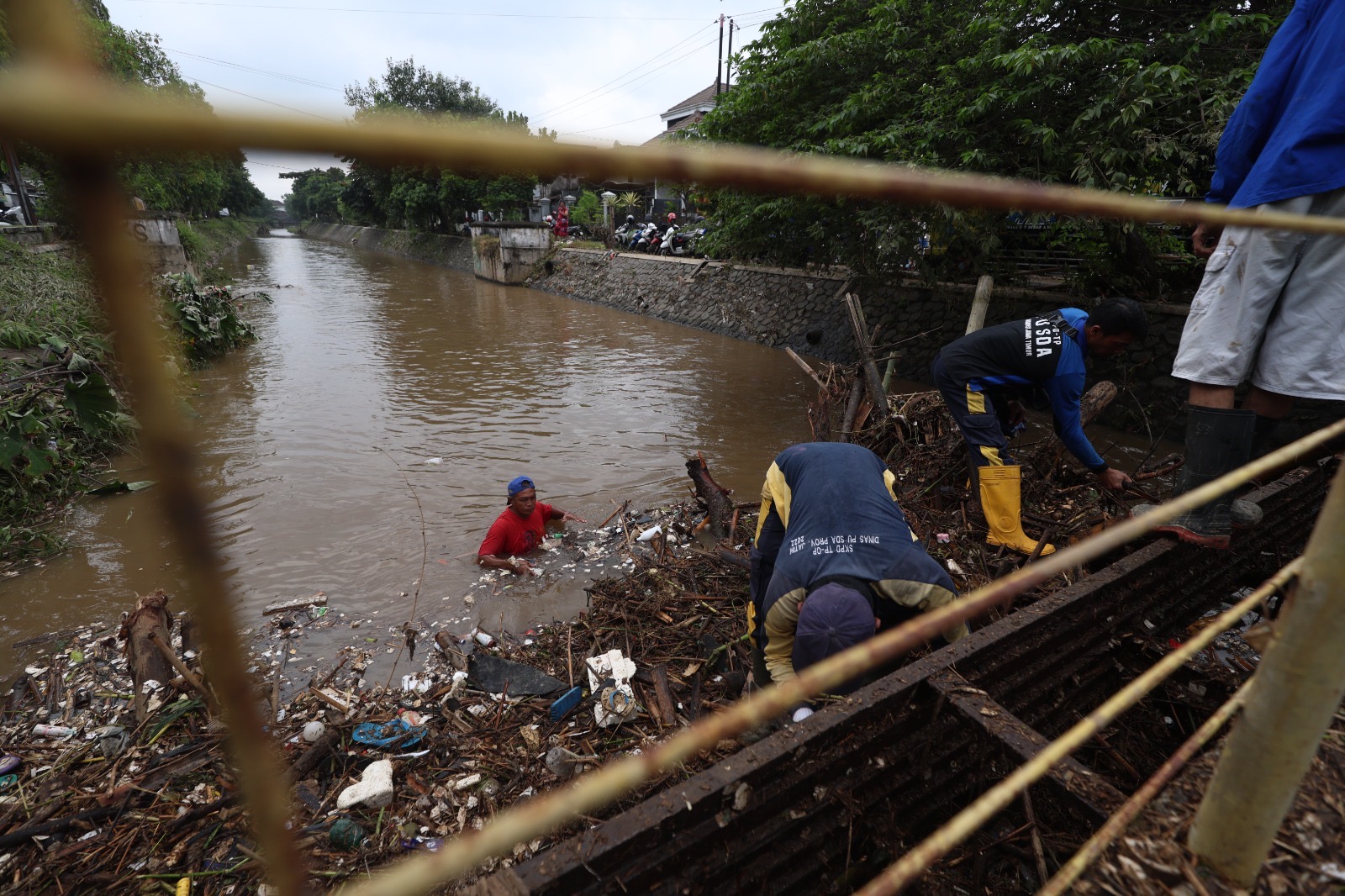 TIDAK BISA LANCAR: Sejumlah petugas dan relawan membersihkansampah, potongan kayu, dan rumpun bambu yang tersangkut di jembatanSungai Sirinjing, Desa Tertek, Pare kemarin pagi.