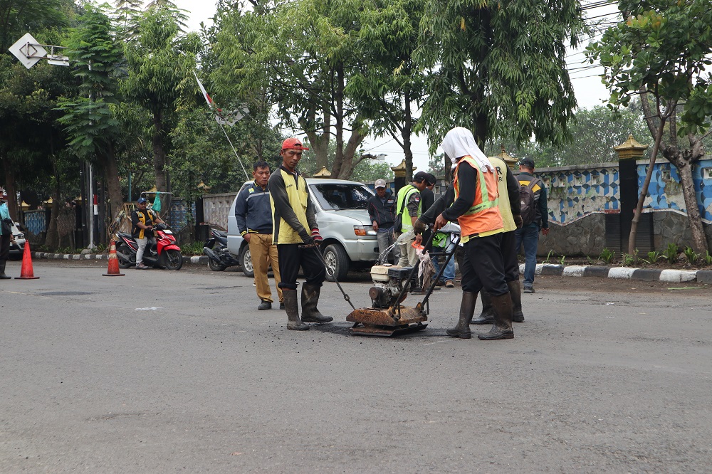 Petugas Dinas PUPR Kota Kediri menambal jalan berlubang di Jl Imam Bonjol. Pemeliharaan rutin dilakukan sembari menunggu pelaksanaan proyek perbaikan pekan ini.