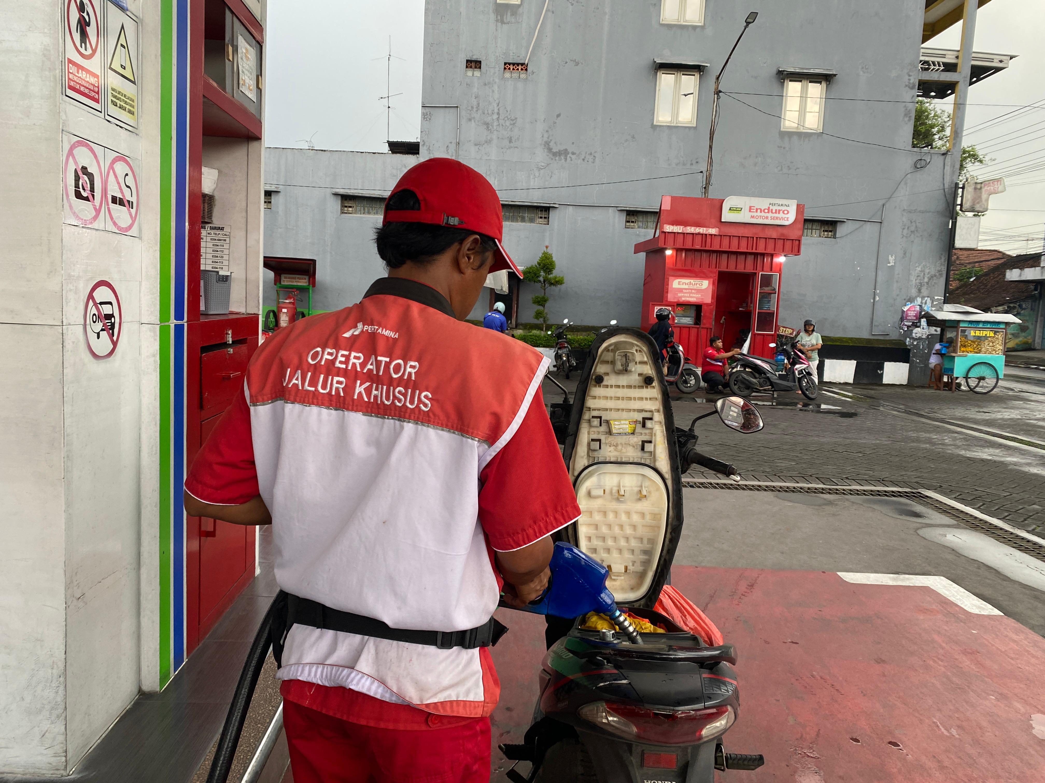 Petugas SPBU sedang melayani pembelian bensin Pertamax.