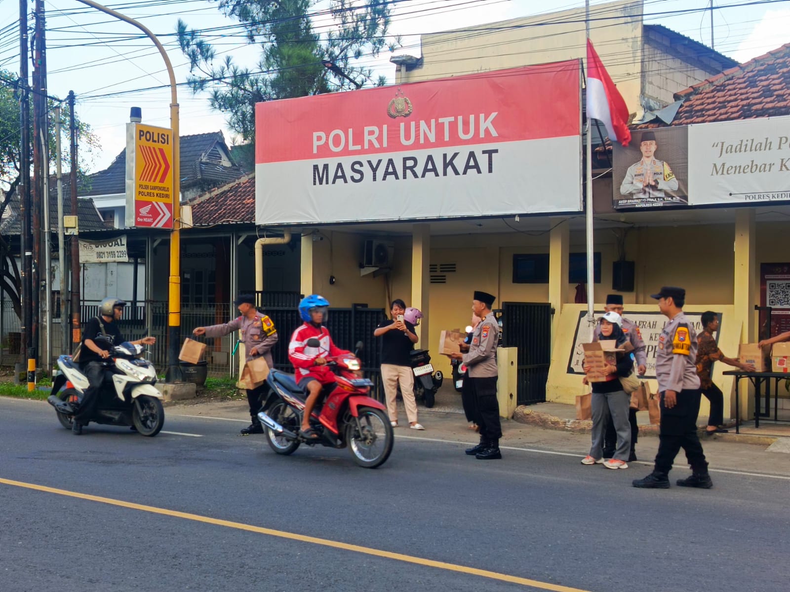 BERBAGI: Personel Polsek Gampengrejo membagikan takjil kepada pengguna jalan di depan mako polsek, Rabu (4/3). (FOTO: POLSEK GAMPENGREJO)  &nbsp;  