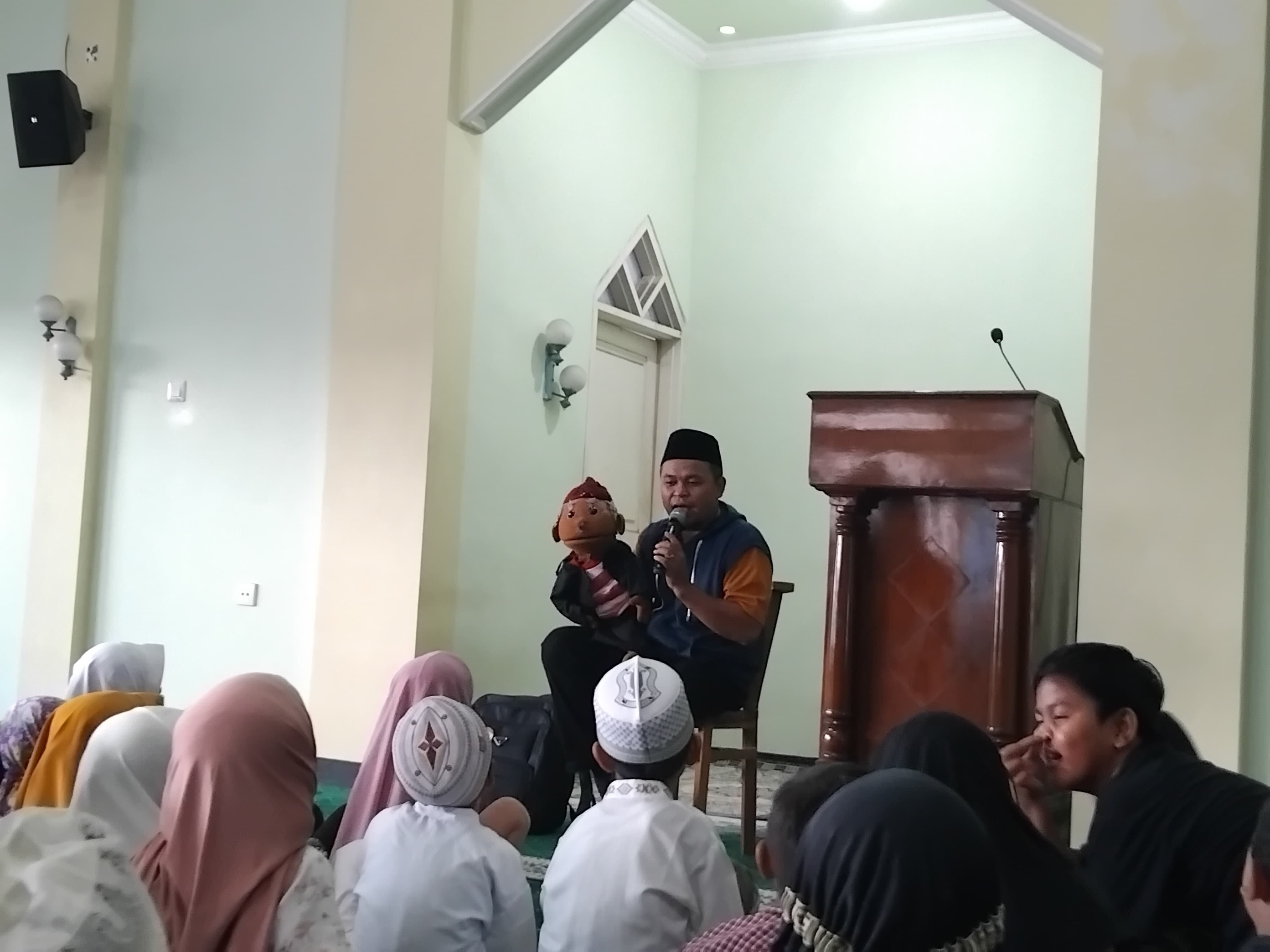 Kang Aji membacakan dongeng kepada anak-anak dengan media boneka (Diana Yunita)
