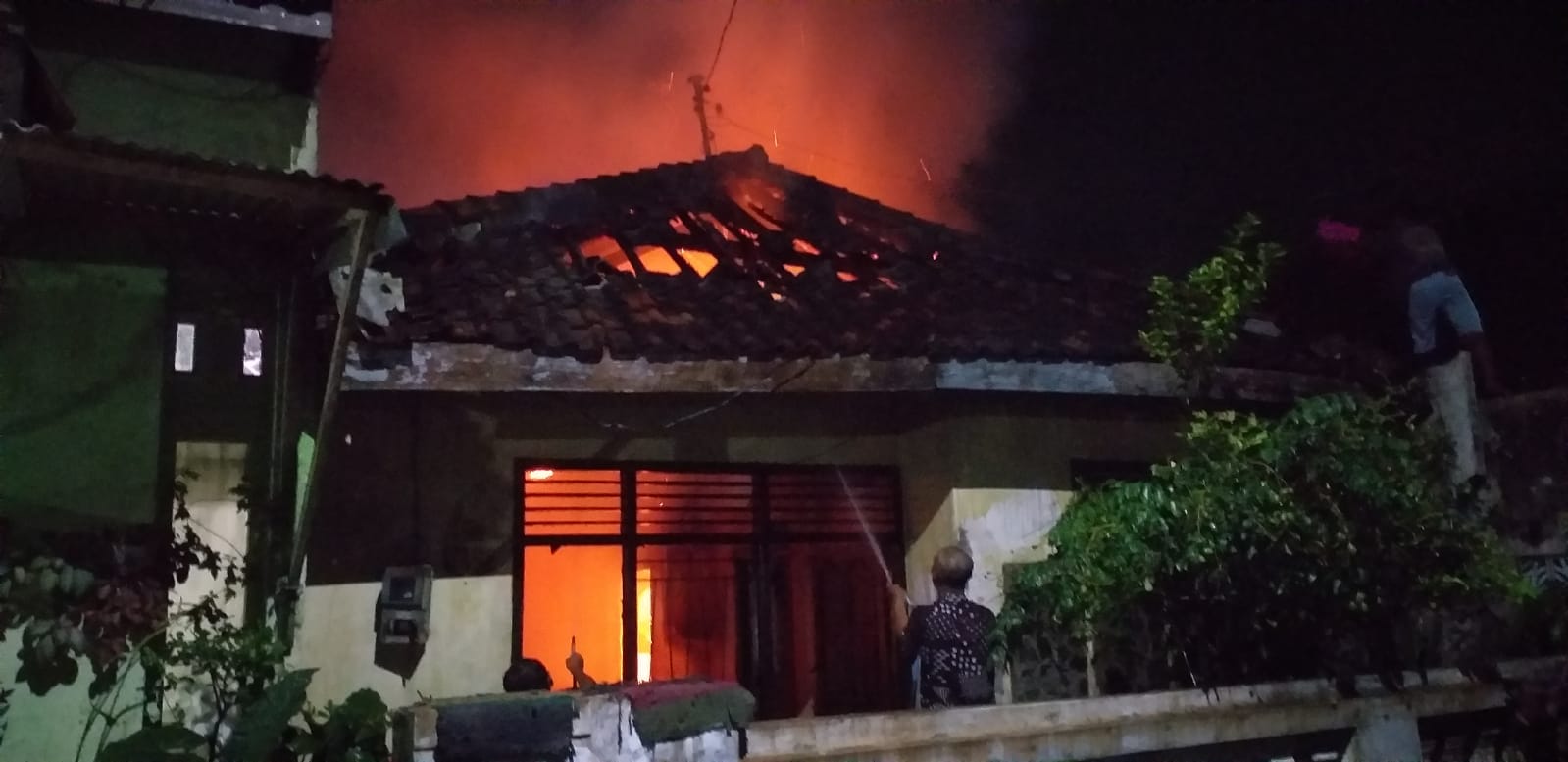 Petugas melakukan pemadaman api di rumah warga Desa Brenggolo Kecamatan Plosoklaten 