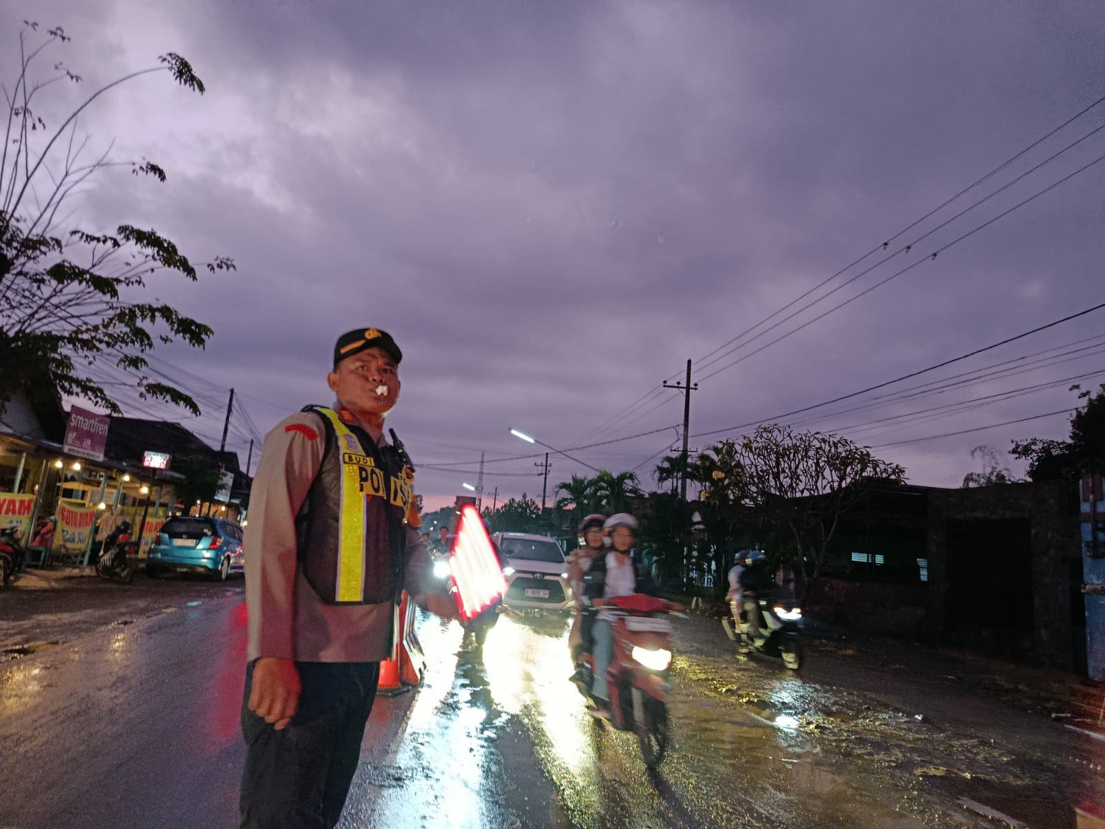 Kapolsek Ngadiluwih melakukan pengaturan jalan saat hujan 