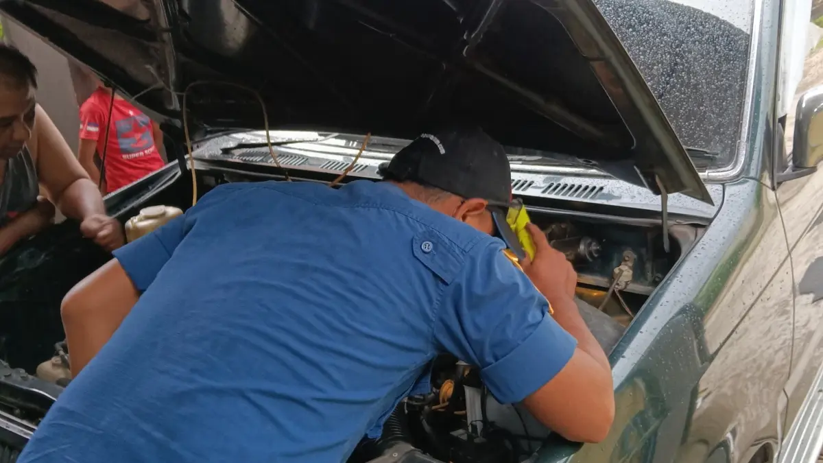 Petugas Damkar melakukan evakuasi ular yamg bersembunyi di sasis mobil warga Desa Damarwulan