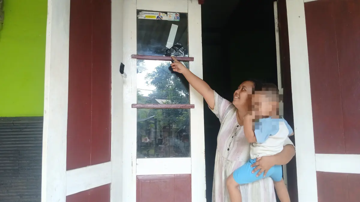 Pemilik rumah menunjukkan kacanya yang pecah diduga karena tembakan senapan angin. (Thoni)