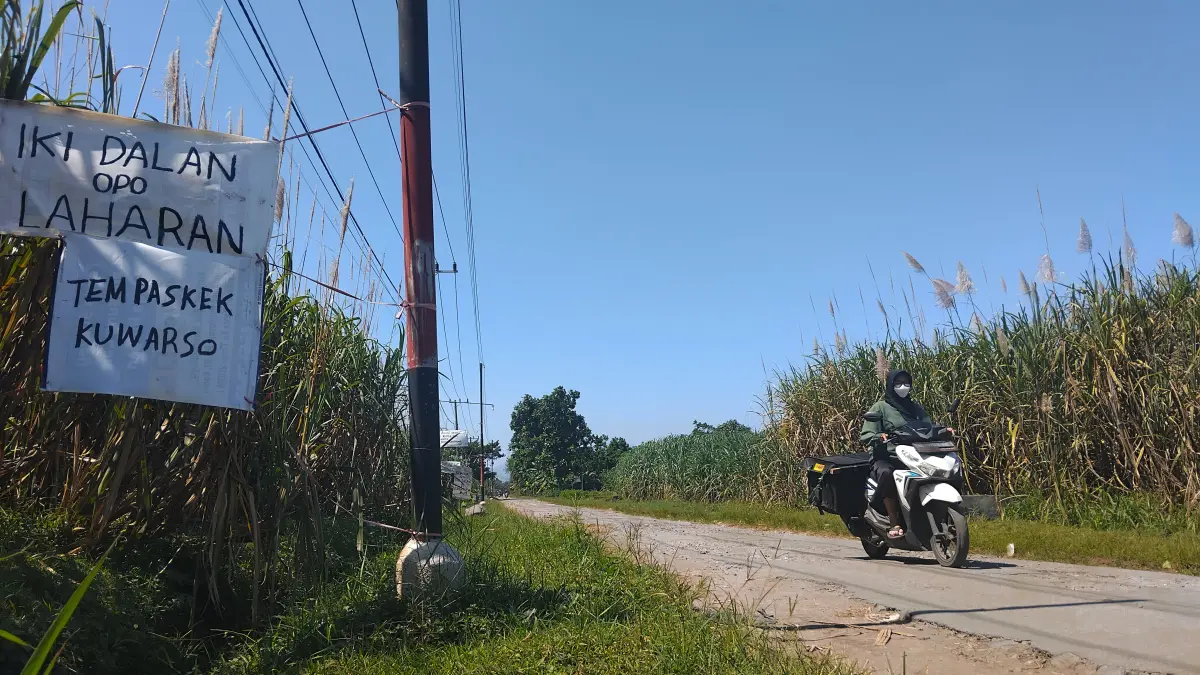 PROTES: Spanduk bernada protes terkait kerusakan jalan raya dipasang oleh warga Desa Sumberagung, Plosoklaten. Kondisi jalan tersebut menjadi keresahan warga selama ini. (DIANA YUNITA SARI/JPRK)
