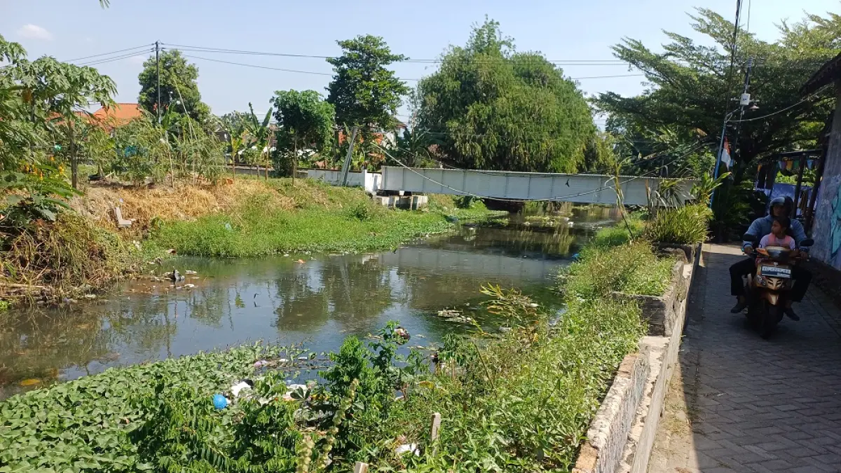 KERUH DAN BERBAU: Warga melintas di dekat Sungai Parung di Kelurahan Kampungdalem. (Foto: Wahyu Adji)