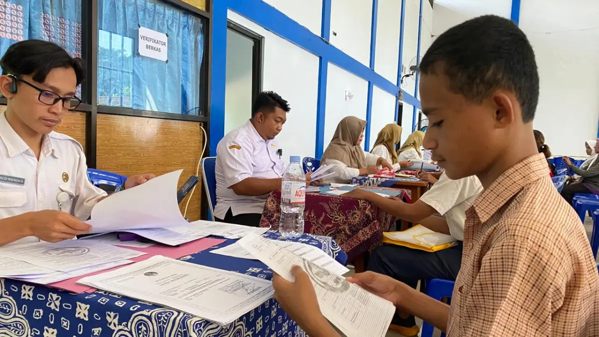 CERMAT : Petugas verifikasi SMKN 1 Kota Kediri mengecek dokumen yang telah dibawa oleh pendaftar. (Hilda Nurmala Risani/JPRK)