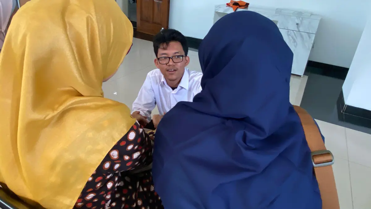 Ahmad Faiz Yusuf mengenggam kedua tangan ibunya sebelum persidangan di PN Kediri dimulai. (Hilda Nurmala Risani/JPRK)
