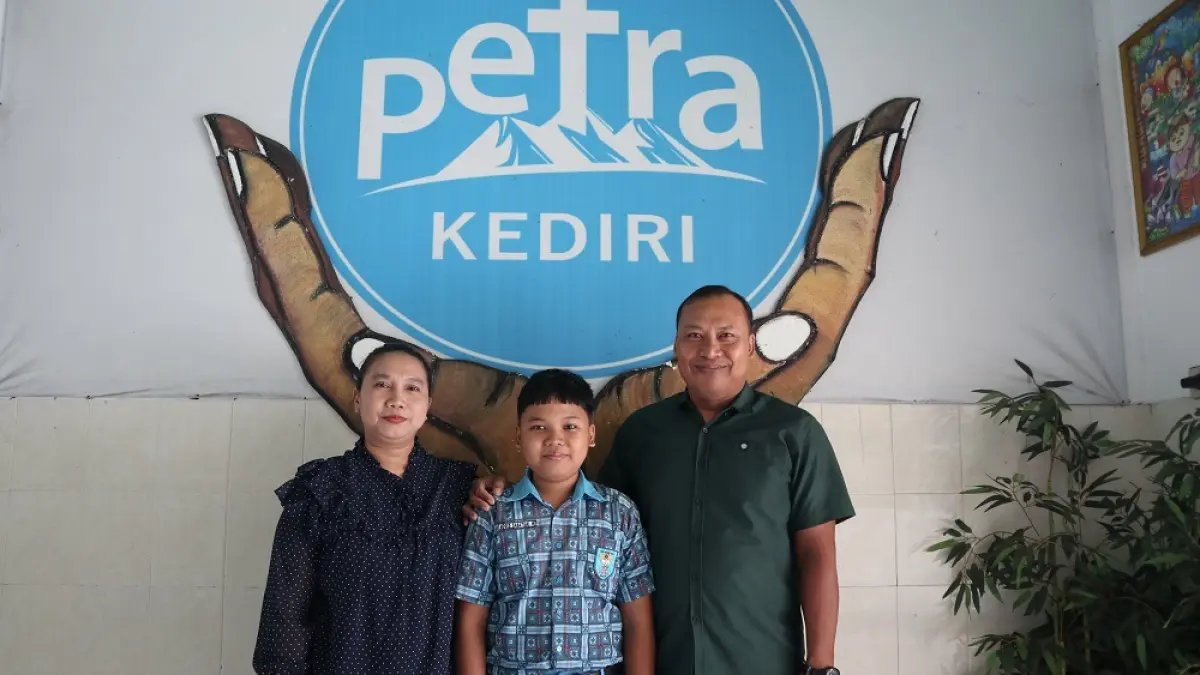 Moses Sabatian Wicaksono, siswa SD Kristen Petra Kediri peraih nilai TKA SD tertinggi di Kota Kediri, berfoto bersama kedua orang tuanya. (Foto: Ayu Isma)