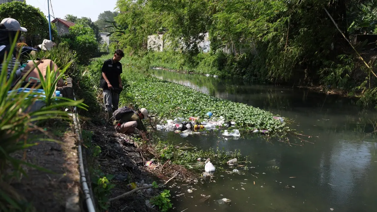 PENUH SAMPAH DAN TANAMAN AIR: Mahasiswa Prodi Pendidikan Biologi UNP Kediri mengambil sampel air di Sungai Parung, Kelurahan Kampungdalem. Limbah domestik, sampah plastik, hingga ledakan tanaman air jadi ancaman kelestarian sungai yang bermuara di Sungai Brantas tersebut. (Foto: Wahyu Adji)