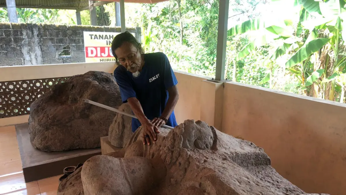 Juru kunci Situs Kala di Desa Nambaan membersihkan arca (Diana Yunita/JPRK)