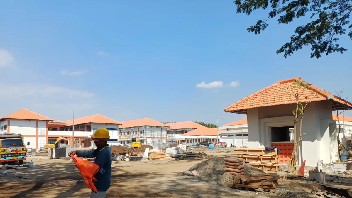 KEBUT FISIK: Pekerja fokus menyelesaikan pembangunan sejumlah bangunan di kompleks Sekolah Rakyat Kota Kediri di Kelurahan Lirboyo, Mojoroto. Hingga Senin (15/6) lalu, progres baru mencapai 85 persen. (Foto: Ayu Isma)