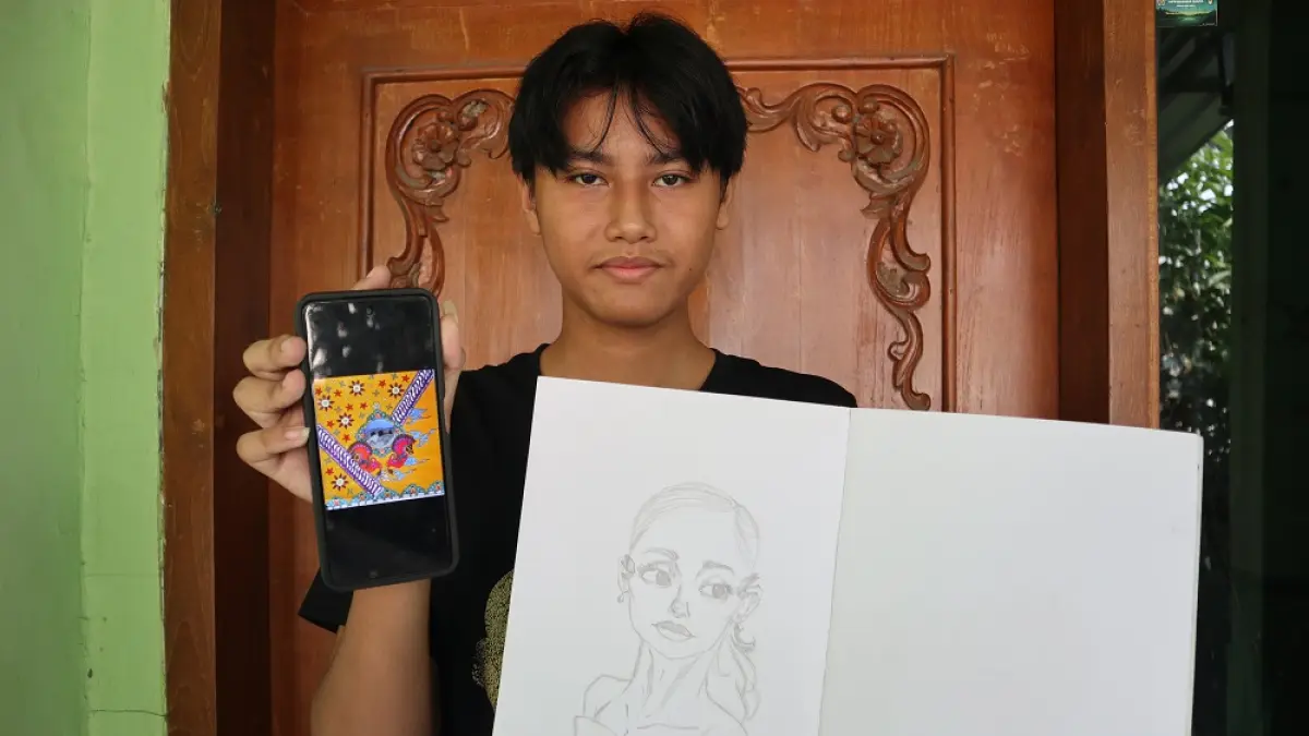 Beryl Aiko menunjukkan karya desain batiknya (foto di handphone) dan salah satu karya gambar animasi yang digelutinya. (Foto: Ayu Isma)