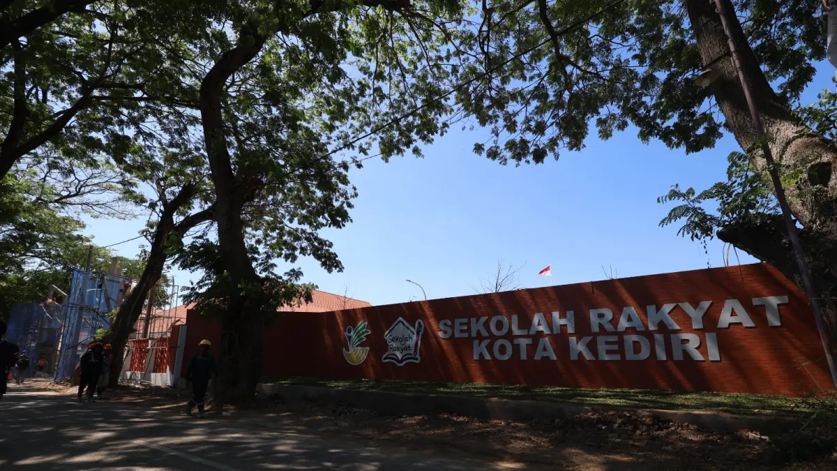 TERUS BERPROSES : Seorang pekerja berjalan di depan kawasan proyek Sekolah Rakyat di Kota Kediri. Progress pembangunan mencapai 89 persen per Senin (29/6). (Wahyu Adji/JPRK)