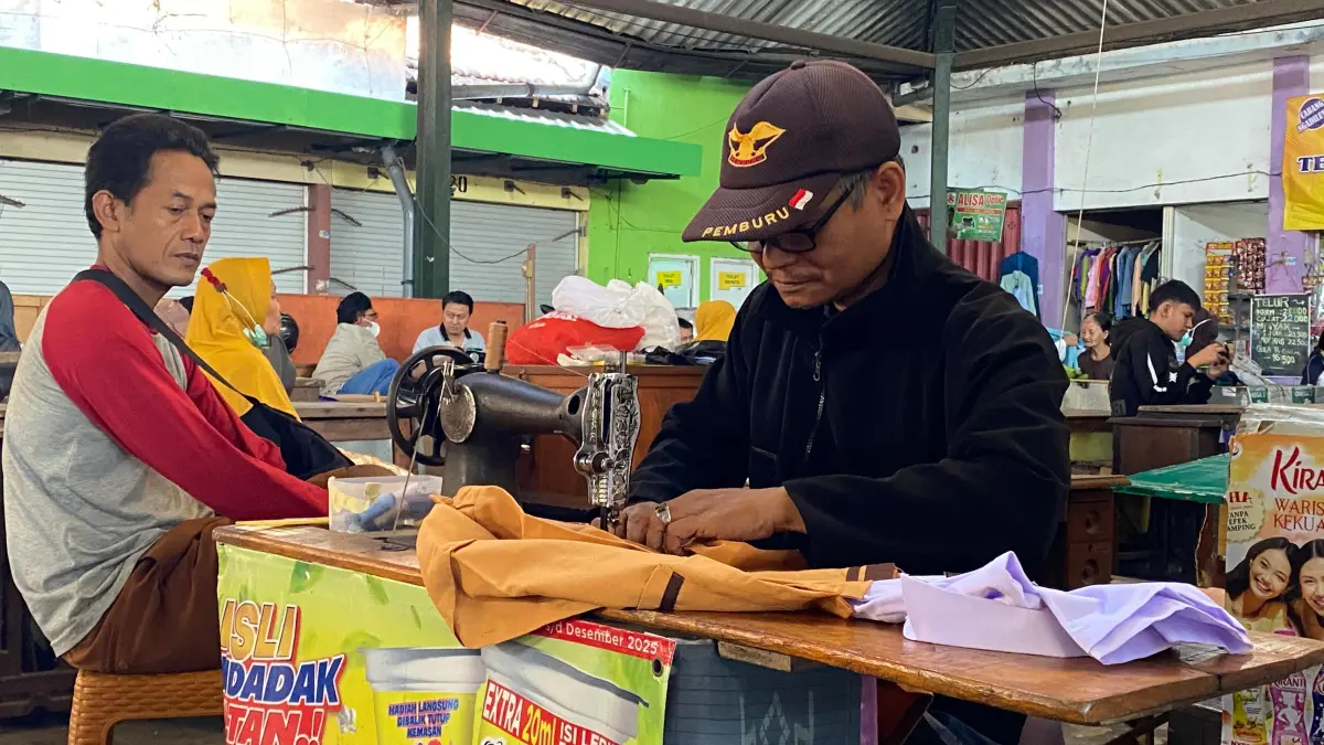 Salah seorang penjahit di Pasar Pahing, Kota Kediri sedang melayani pelangganya. (Hilda Nurmala/JPRK)
