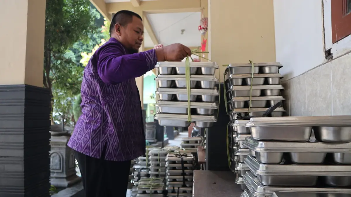 RAPIKAN OMPRENG: Badrul Munir, guru SDN Bangsal 3 menata kotak makan paket MBG yang baru dikonsumsi ratusan siswa di sekolahnya kemarin (16/7). (Foto: Ayu Isma)
