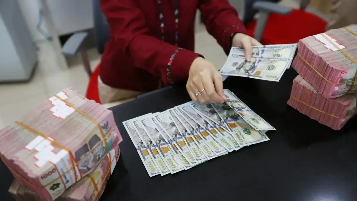 Petugas money changer sedang menghitung pecahan uang Dolar Amerika Serikat (USD) dan Rupiah (IDR) di salah satu gerai penukaran mata uang asing. (Dery Ridwansah / JawaPos.com)