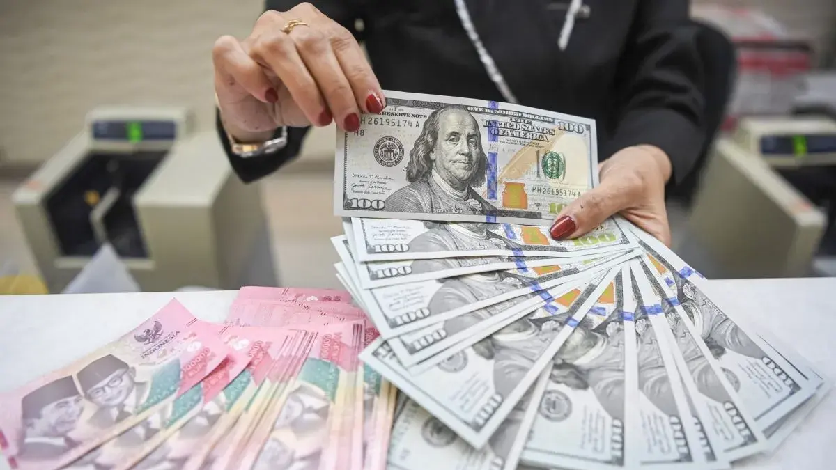 Karyawan tersebut terlihat sedang menghitung dan mengatur tumpukan uang kertas pecahan Rupiah (IDR) dan Dolar Amerika Serikat (USD) Ayu Masagung di Jakarta, Senin (13/7/2026). (Risyal Hidayat/foc)