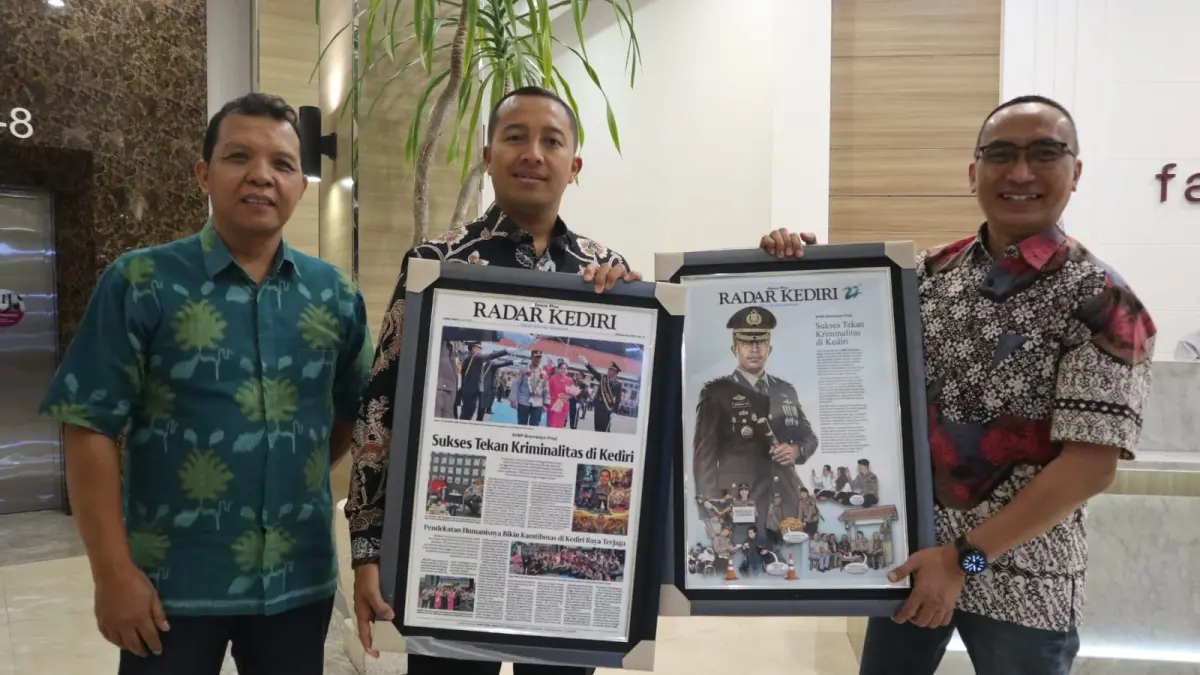 Direktur JP Radar Kediri Kurniawan Muhammad (kanan) berpose bersama AKBP Bramastyo Priaji (tengah)usai menyerahkan cenderamata berupa halaman koran yang berisi berita tentang aktivitas AKBP Bram ketika menjabat Kapolres Kediri.