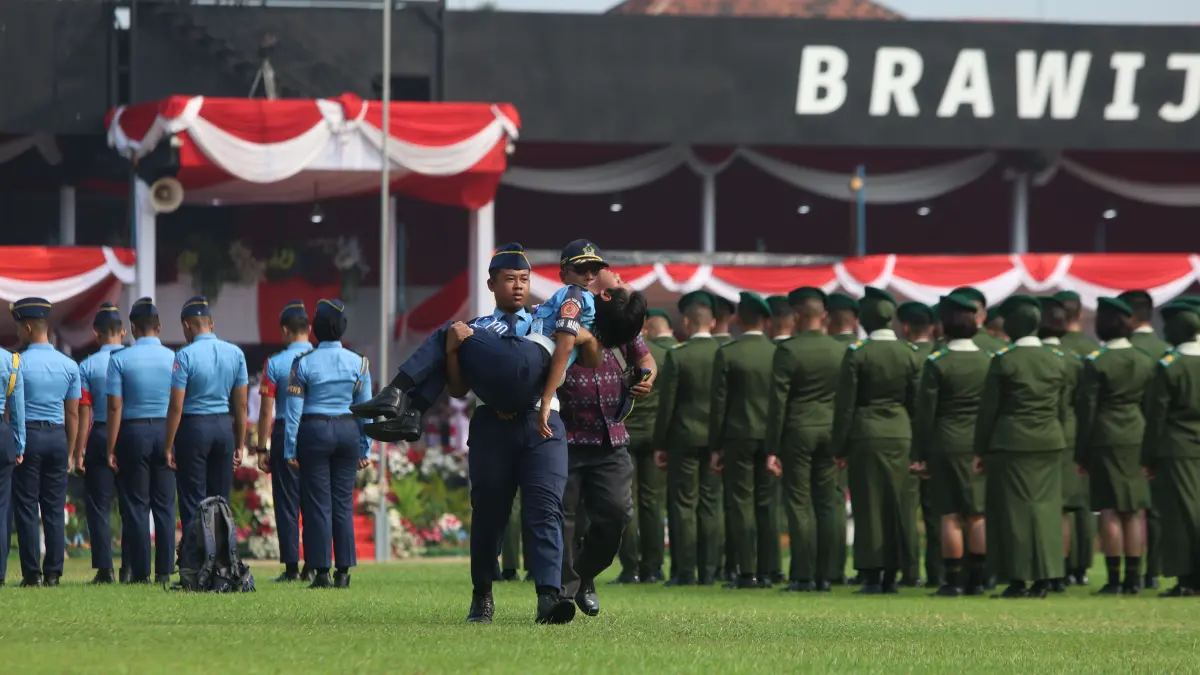 BERI PERTOLONGAN: Siswa membopong peserta upacara yang pingsan di Stadion Brawijaya kemarin pagi agar bisa segera ditangani petugas kesehatan yang bersiaga di pinggir. (Wahyu ADJI/JPRK)