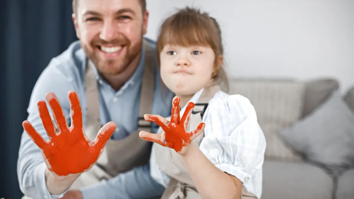 Gadis dengan Down syndrome dan ayahnya mengecat tangan dengan warna merah (freepik)