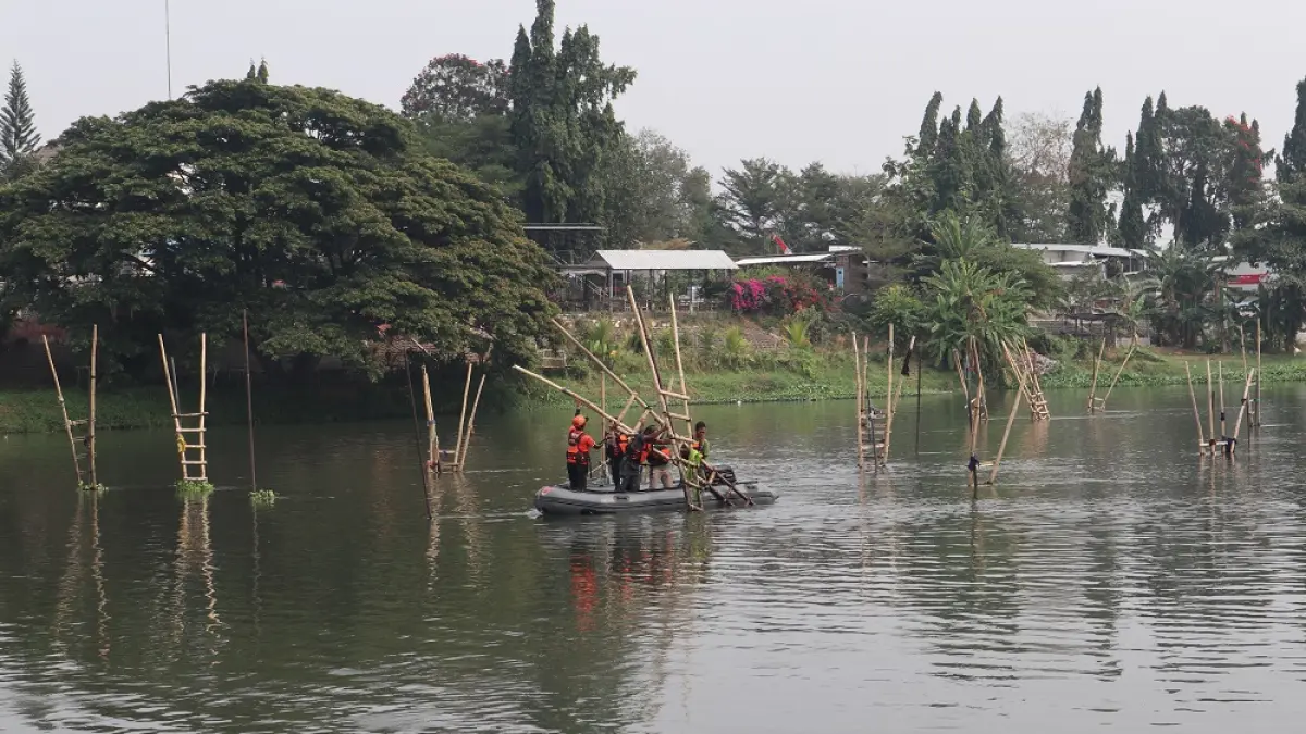 Petugas Satpol PP bersama BPBD Kota Kediri dan koordinator paguyuban penambang pasir mencopoti tiang besi dan tangga bambu yang biasa dipakai sandaran perahu penambang pasir di utara Jembatan Brawijaya, Kelurahan Mojoroto, Kota Kediri. (Foto: Ayu Isma)