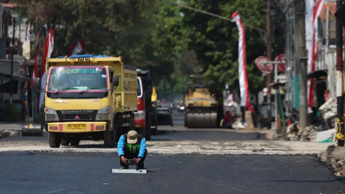 Pekerja melakukan pengecekan hasil pengaspalan jalan di Jembatan Kaliombo, Kota Kediri (21/8). BBPJN mengonfirmasi arus lalin akan mulai dibuka Sabtu malam (22/8). (Foto: Wahyu Adji)