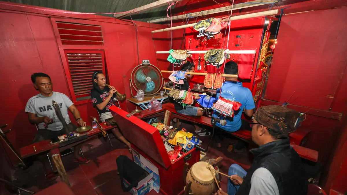 DI BALIK PANGGUNG: Tiga orang memainkan alat musik Tiongkok untuk mengiringi dalang wayang Potehi yang beraksi ketika tampil di Kelenteng Tjoe Hwie Kiong, Kota Kediri.&nbsp;(Foto: Wahyu Adji)