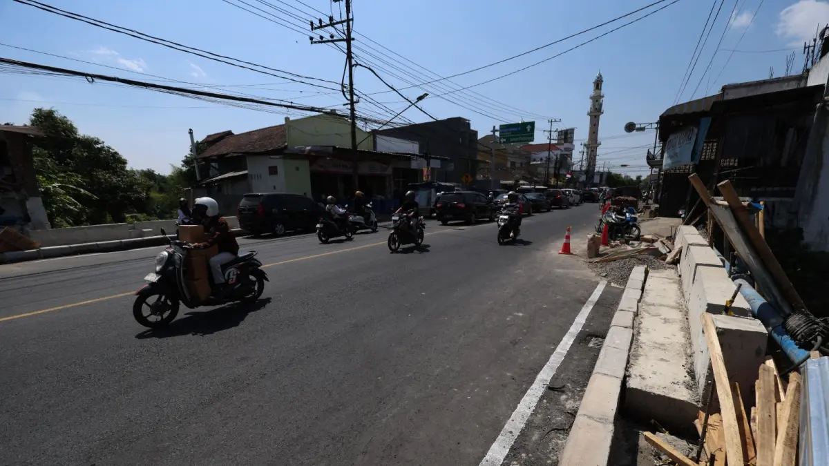 
JALUR VITAL: Pengendara melintasi Jembatan Kaliombo I yang telah dibuka untuk umum. Kini, pekerja memasang kereb trotoar. (WAHYU ADJI F/JPRK)

